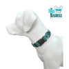 A white dog mannequin models a blue and black waterproof collar, featuring a quick release buckle. A circular tag accents the look, while "The Dogs Business Pet Shop" logo with a stylized dog in sunglasses is prominently in the top right corner.