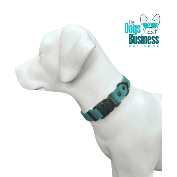 A white dog mannequin models a blue and black waterproof collar, featuring a quick release buckle. A circular tag accents the look, while "The Dogs Business Pet Shop" logo with a stylized dog in sunglasses is prominently in the top right corner.
