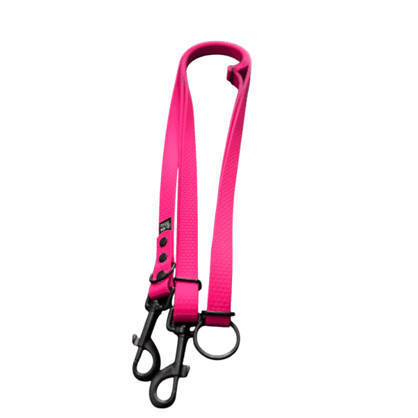 The Waterproof HANDS FREE ADJUSTABLE LEAD FOR DOGS, L 2,5 m is a bright pink dog lead splitter with two black metal swivel clasps and a metal O-ring, perfect for walking two dogs at once. Pictured on a plain white background.