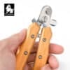 A hand holds the Bamboo Pet Nail Clipper with Safety Guard – Dog & Cat Grooming, featuring wooden handles and a sharp metal blade. The "Truelove" brand logo with a dog's face appears in the upper left corner.