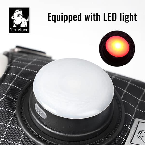 Close-up of the black grid-patterned Truelove TLH6771 LED Dog Harness - GPS Tracker Smart Safety, featuring a white circular LED light glowing red. Text reads "Equipped with LED light." Truelove dog logo in the upper left corner.