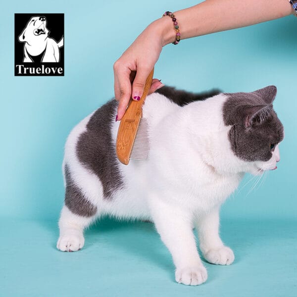 A person brushes a white and gray cat with the Truelove Bamboo Pet Grooming Brush – Stainless Steel Pins against a blue background. The "Truelove" logo with a dog illustration appears in the top left corner.