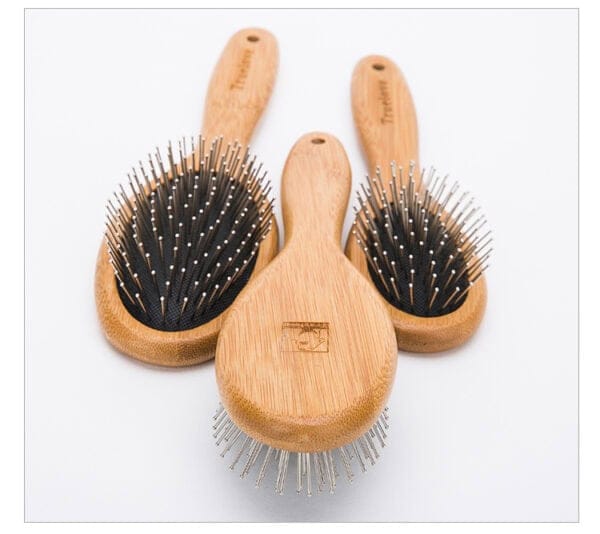 Three wooden hairbrushes with metal bristles are arranged on a white background, with one brush in the front and two slightly behind it, all featuring black cushioned bases.