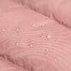 Close-up of the waterproof pink fabric with water droplets on the dog jacket, demonstrating its water-resistant quality for rainy conditions.