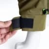 A close-up of the adjustable Velcro strap on the green windproof dog jacket, showing how it secures the fit.