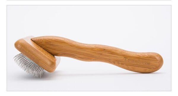 The Truelove Bamboo Pet Comb - Grooming Tool features a curved handle and metal bristles, shown lying on a white surface.