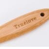 A close-up of the Truelove Bamboo Pet Grooming Brush’s wooden handle, featuring a hole near one end and "Truelove" engraved on it, with stainless steel pins for pet grooming.