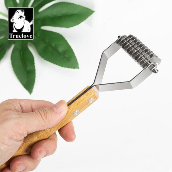 A hand holding the Truelove Bamboo Molting Hair Comb with a bamboo handle and metal blades. A green plant and the Truelove logo appear in the background.