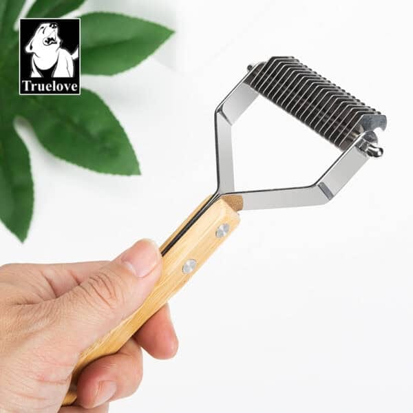 A hand holds the Truelove Bamboo Molting Hair Comb, featuring a bamboo handle and metal comb blades for pet care. A green plant and the Truelove logo appear in the background.