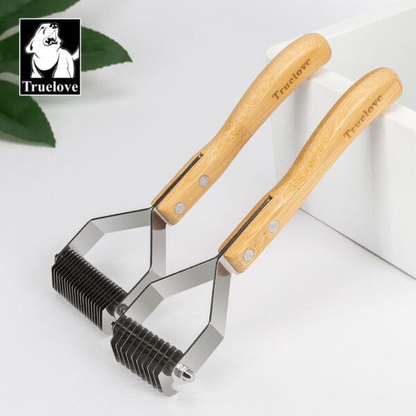 Two Truelove Bamboo Molting Hair Combs with bamboo handles and metal teeth rest on a white surface, with green leaves and a white box in the background.