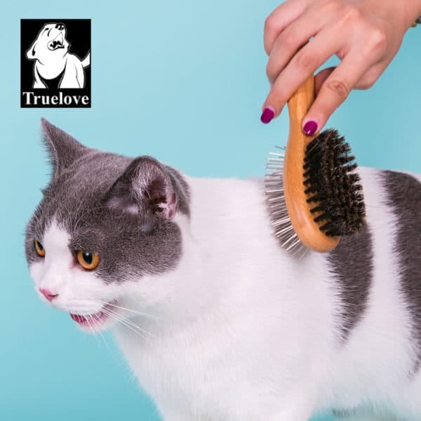 Truelove Bamboo Pet Brush with Boar Bristles - Cat Model A surprised gray and white cat is brushed by hand with the Truelove Bamboo Pet Brush – Stainless Steel Pins & Boar Bristles. The Truelove logo with a dog appears in the top left on a light blue background.