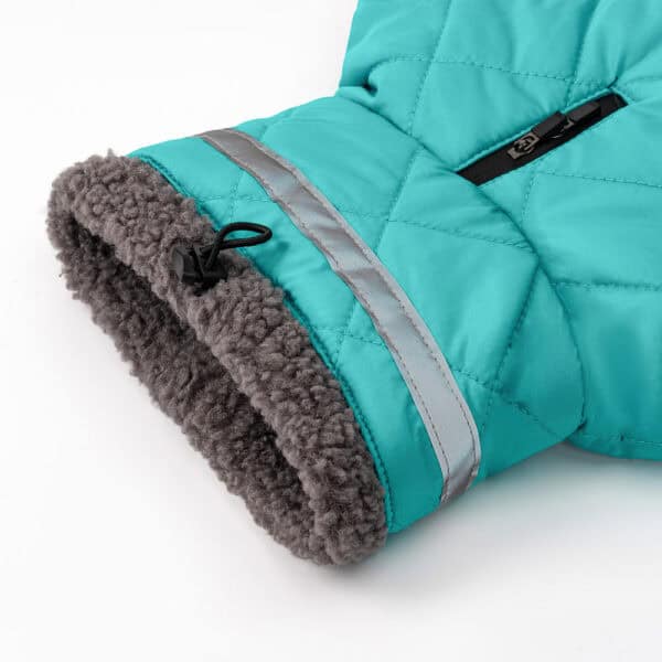 A close-up of the Luxury Polyester Dog Coat, a designer winter pet jacket featuring a turquoise quilted sleeve with black zipper, reflective silver stripe, gray faux fur lining, and black drawstring near the cuff.