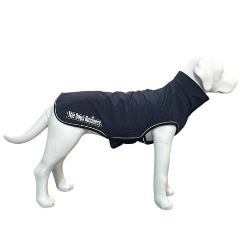 A white dog mannequin wears a dark blue dog coat with white trim and "The Dogs Business" logo on the side, displayed against a plain white background.