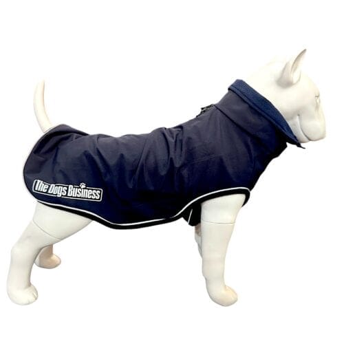 A white dog mannequin wears the TDB Element Jacket, a navy blue coat with a collar and white trim. "The Dogs Business" logo appears on the side. The background is plain white.