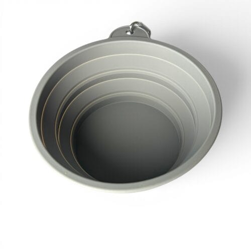 A top-down view of the Coolapsible Dog Travel Bowl, a grey collapsible silicone cup with a metal carabiner on its handle, set against a white background.