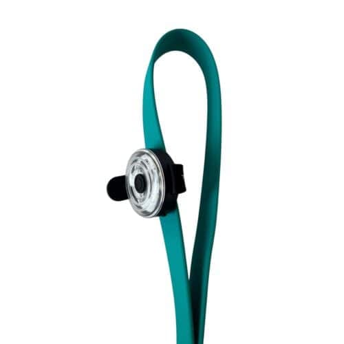 The Dogs Business Safety Light—a teal silicone bike light with a round clear lens and black clip—features a flexible, looped strap for easy bicycle attachment, shown against a white background.