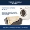 A grey pet bed with a cream Velour Snuggle Blanket next to a washing machine, featuring text with washing instructions and dimensions.